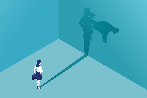 Illustration of a woman facing a wall looking at her shadow. Her shadow is her with a superhero cape on.