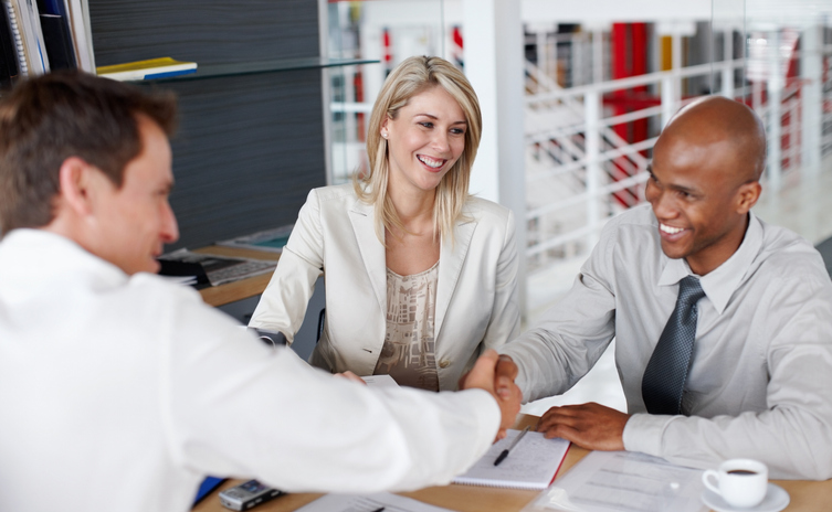 Male partners shaking hands after a business deal at desk