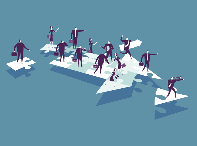 An arrow being formed out of puzzle pieces with cartoon business people on top of the puzzle pieces and a leader at the front