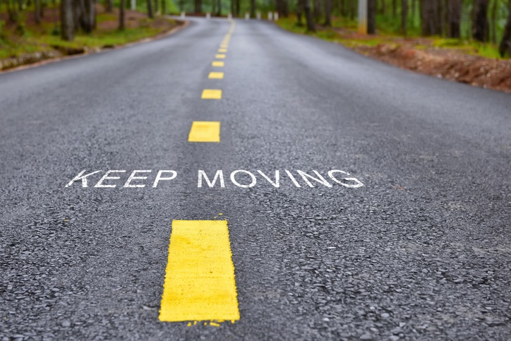 A road with yellow lines in the middle and the words "keep going"