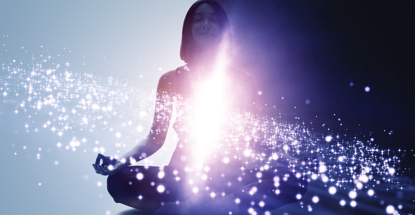 Photo of a women sitting cross-legged with a bright purple light/aura in the middle of her body