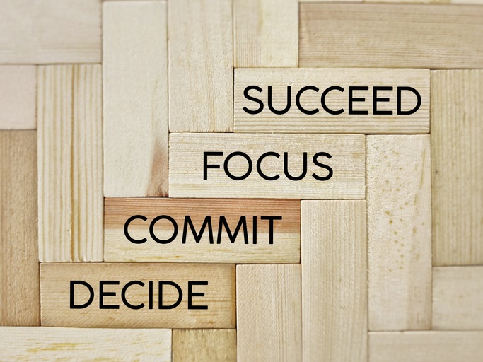Wooden blocks with the words "decide", "commit", "focus", "succeed"