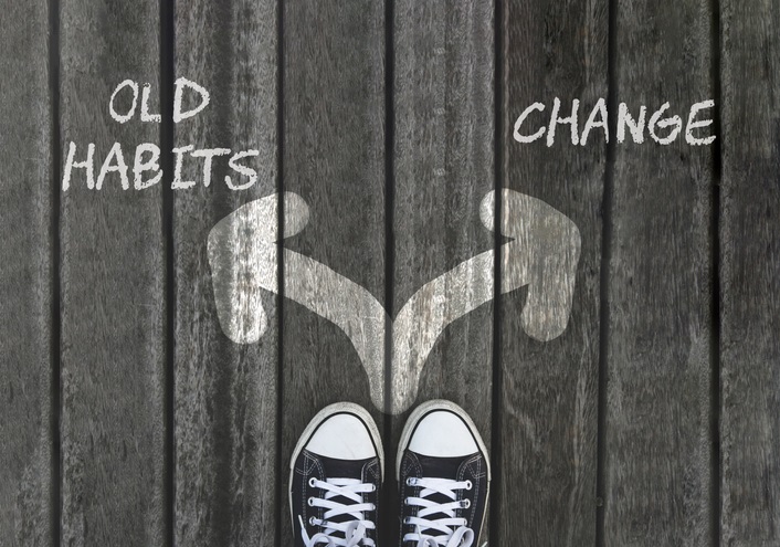 Two arrows drawn on the ground with a pair of shoes facing them. The arrow pointing left says "old habits" and the arrow pointing right says "change"